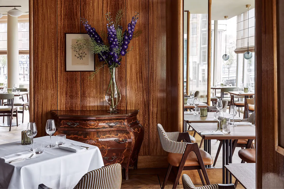 Dining area with wood-paneled walls, carved floral arrangement, and formal service setup