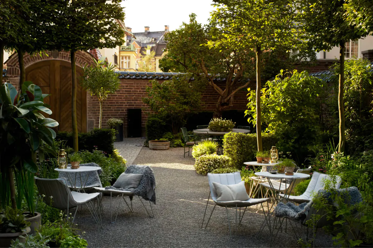 An outdoor garden seating area with white lounge chairs under trees