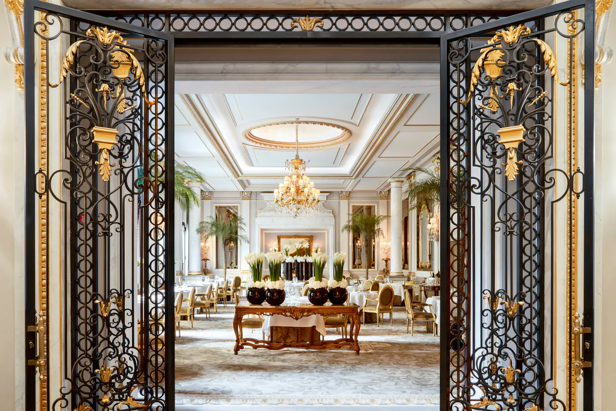A formal dining room with parquet floors, gilt chairs, and a classical ceiling