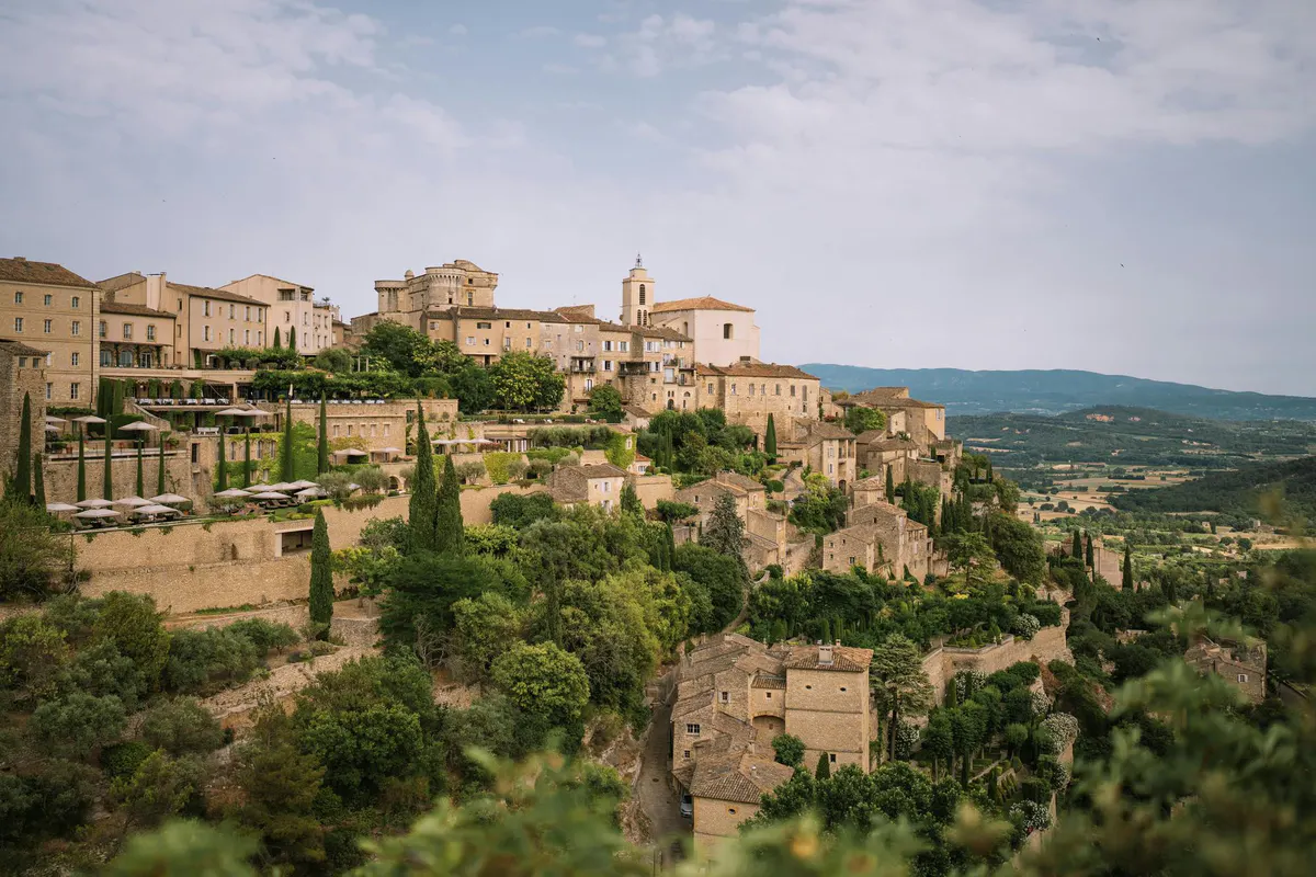 Village on a hillside with stone buildings and cypress trees