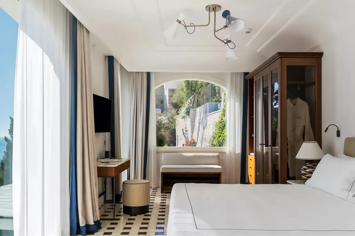 Contemporary bedroom featuring arched window, linen drapes, and Mediterranean views