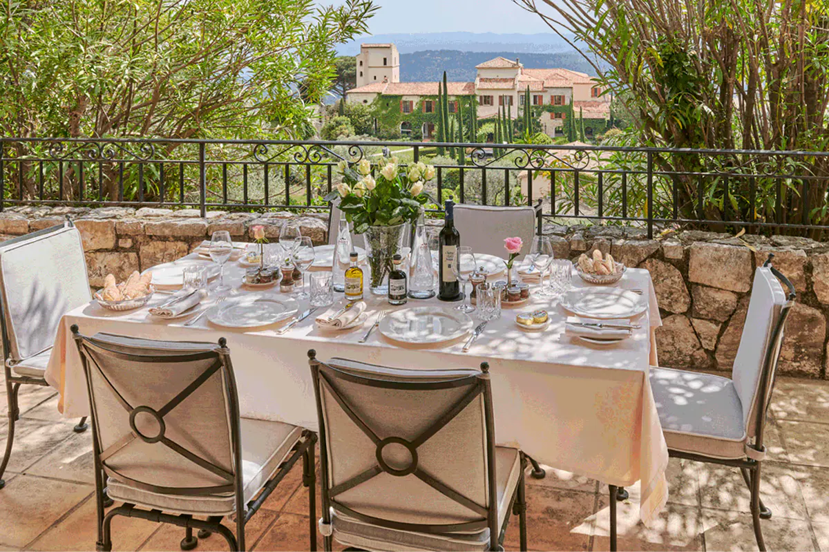 Outdoor dining setup on stone terrace overlooking forested hillside