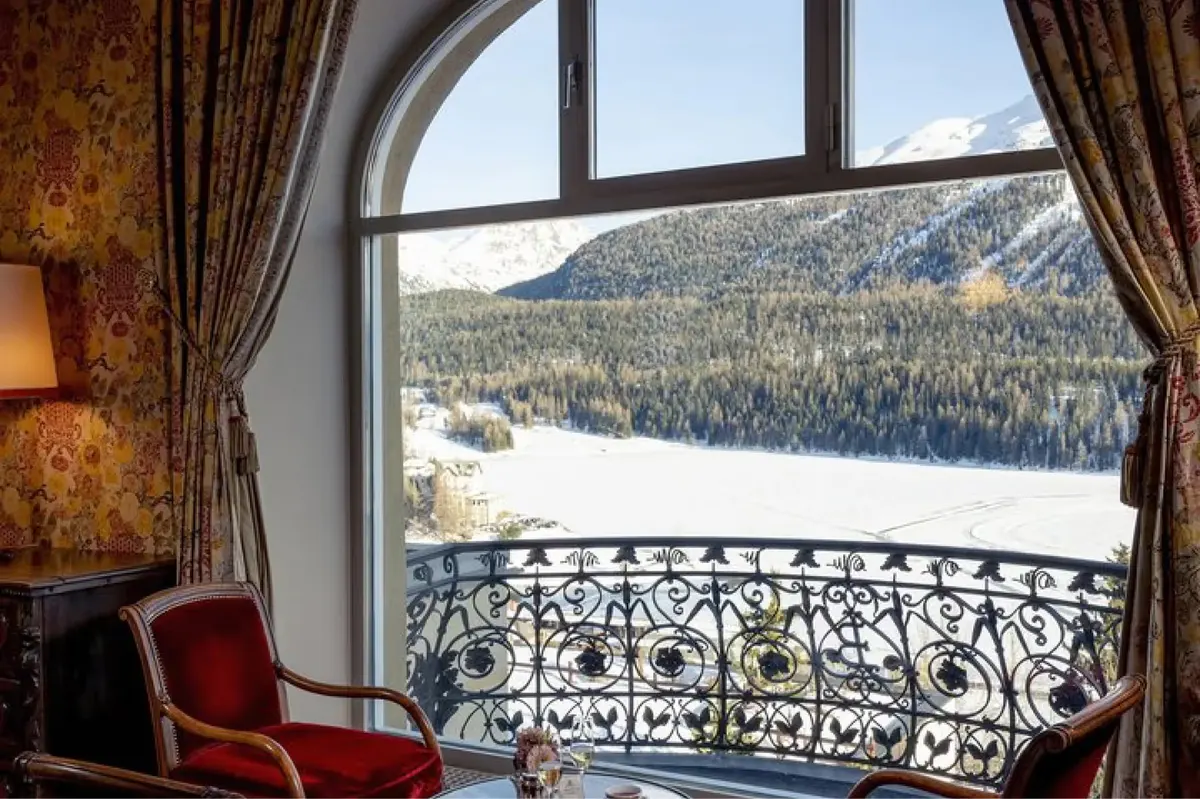 A luxury bathroom in warm wood tones with marble accents and a snow-view window