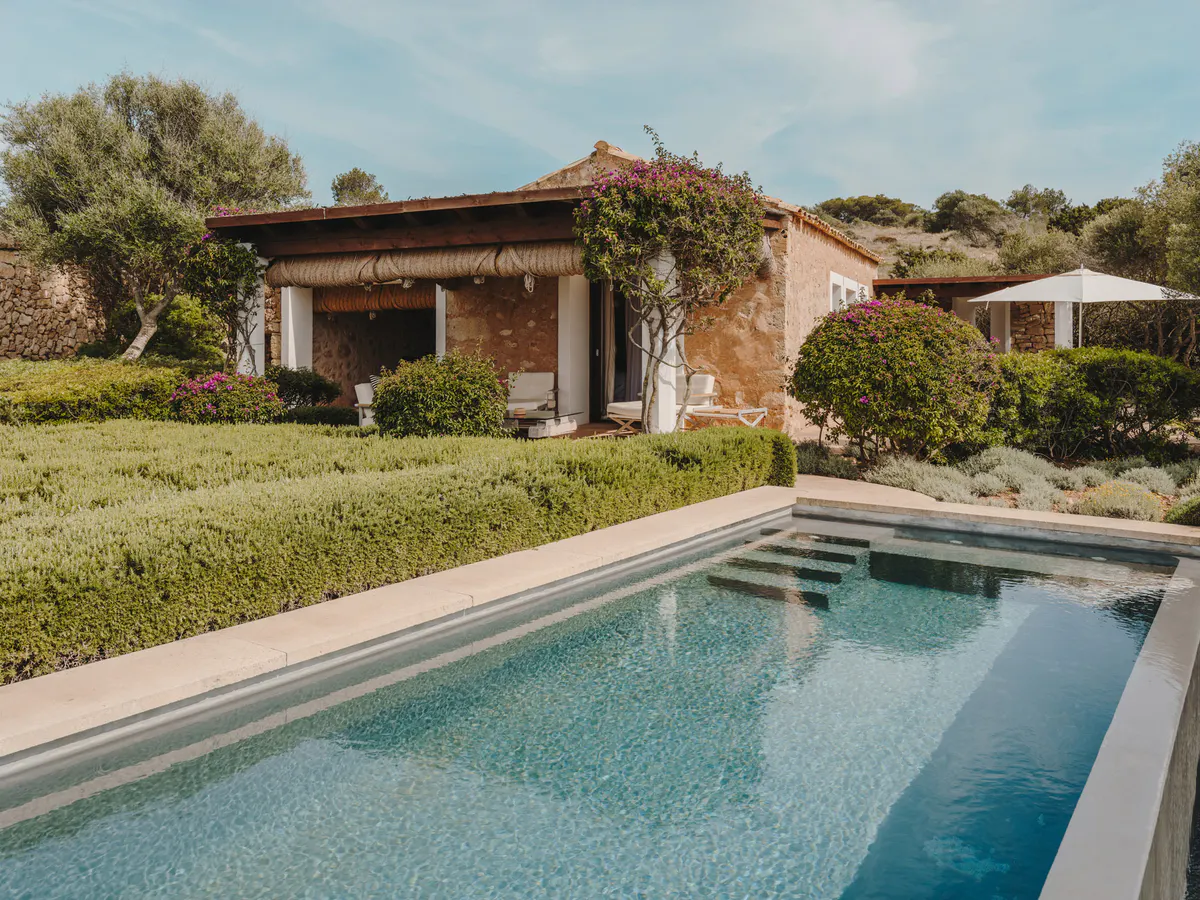 Cushioned loungers and a cream parasol on a stone terrace overlooking the sea