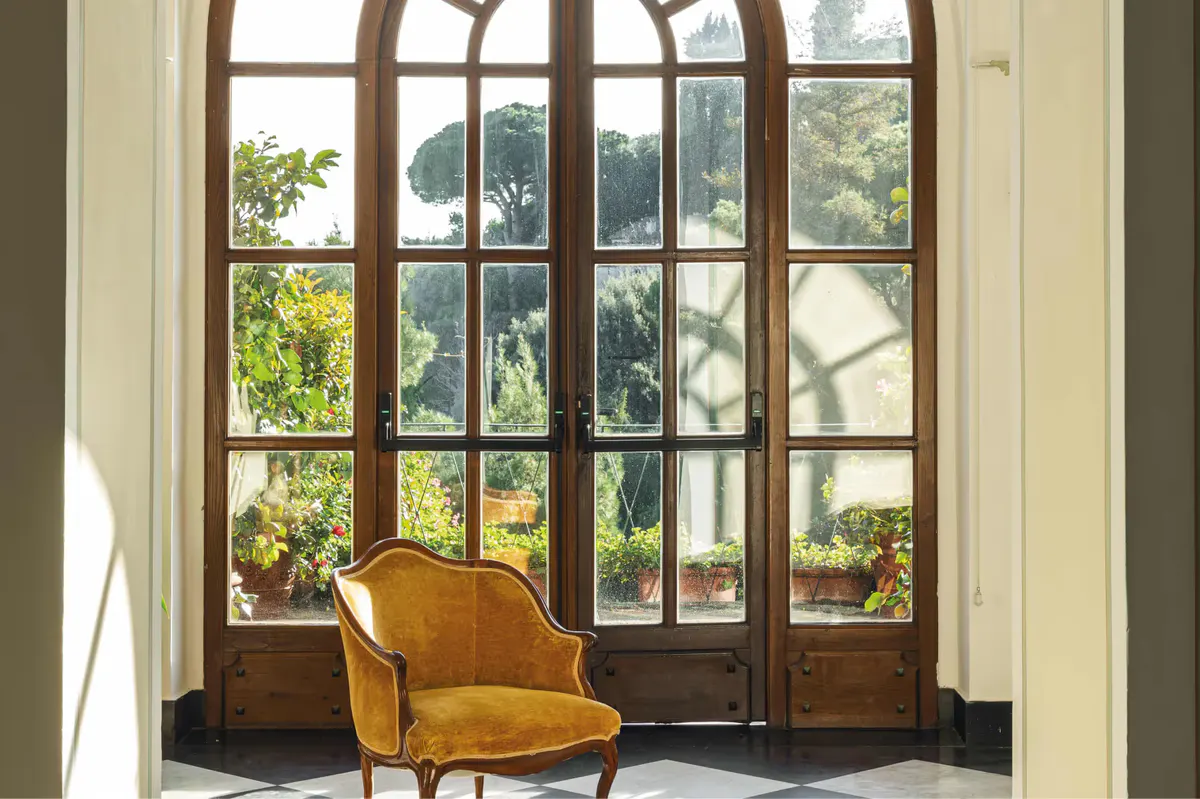 Large wood-framed glass doors with transoms opening to lush green views