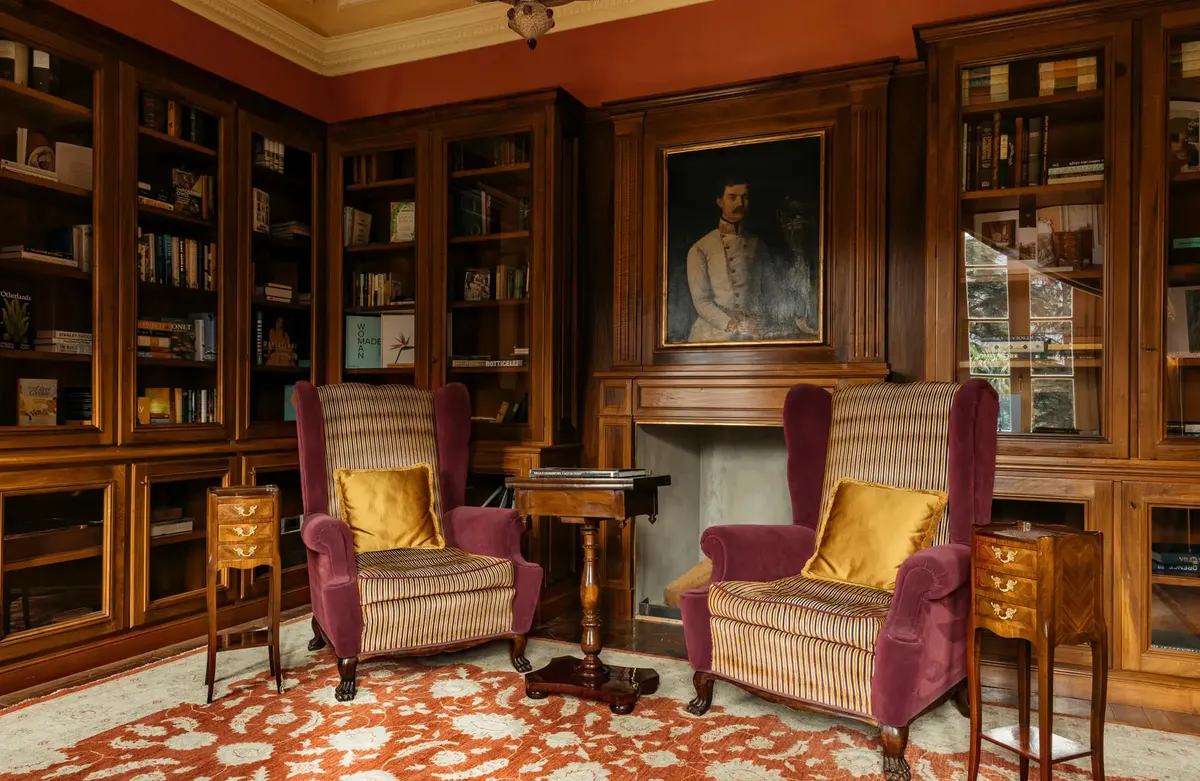 A library with burgundy cabinetry, fireplace, purple velvet seating, and wood paneling