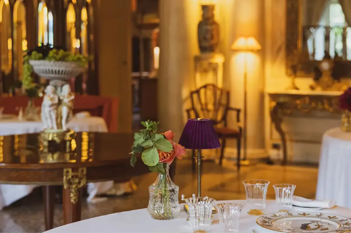 An elegant interior dining room with cream walls, gilded mirrors, and soft lighting