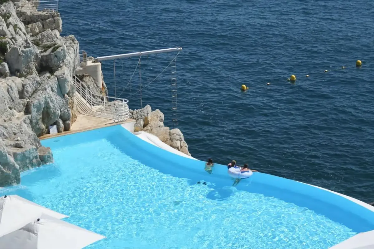 A rocky cliff-carved pool edge overlooking deep blue Mediterranean waters