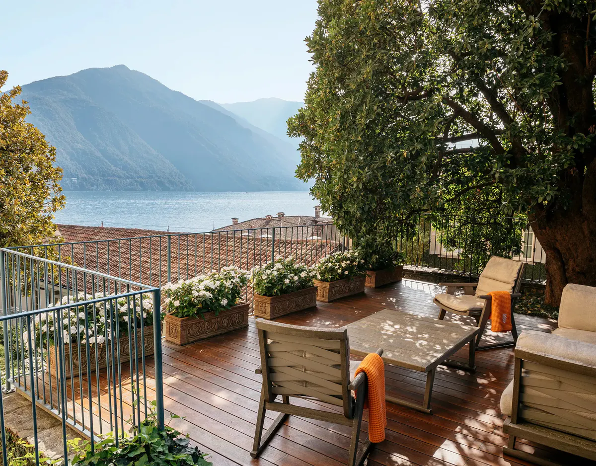 Rooftop terrace with wooden decking, railing, and forested mountain backdrop