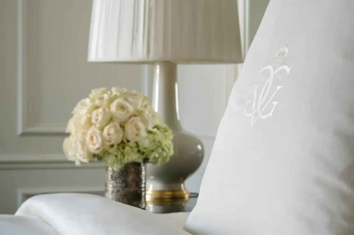 A bedroom with dark wood wardrobes, taupe drapery, and warm gold-toned lighting