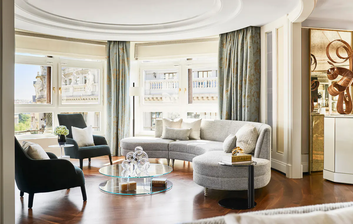 Living area with curved ceiling, gray upholstered seating, wood flooring, and city skyline views