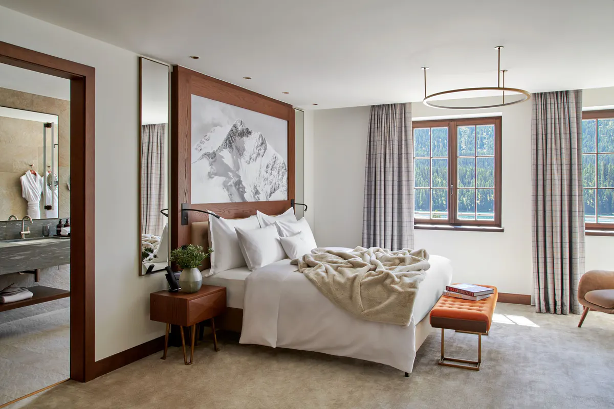 Bedroom with mirrored headboard, accent art, and cream furnishings facing mountain views
