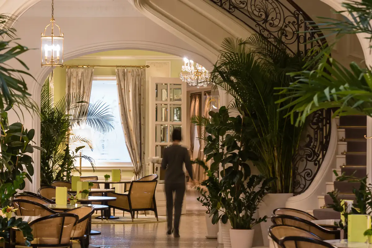 Covered restaurant passageway with soaring ceilings, brass railings and sea view backdrop