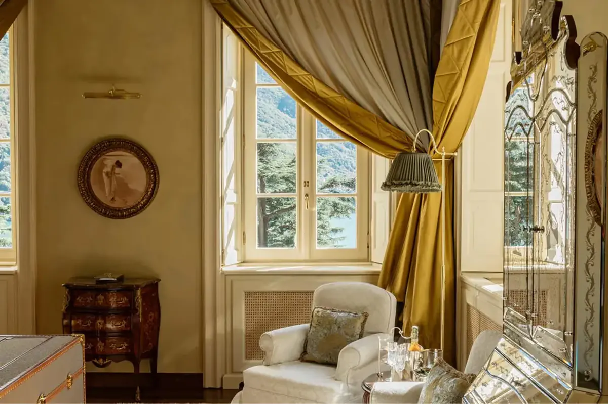 A sitting room with window seating, gold damask curtains, and lake views