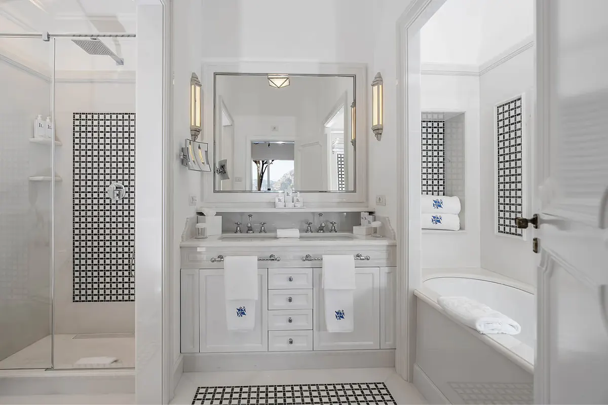 Neutral-toned bathroom with marble vanity, large mirror, brass sconces, and spa-like finishes