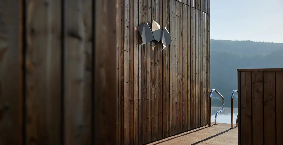 Wooden exterior deck and slatted wall with glass doors and mountains in the distance