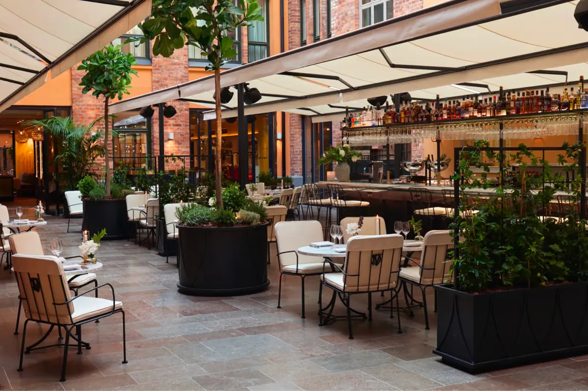 Outdoor terrace dining with planted seating areas and covered umbrellas