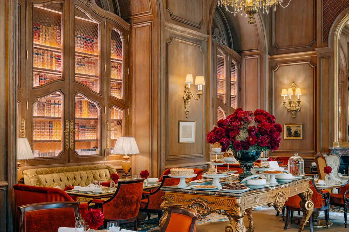 A dining room with wood cabinetry, red upholstered chairs, and floral arrangements