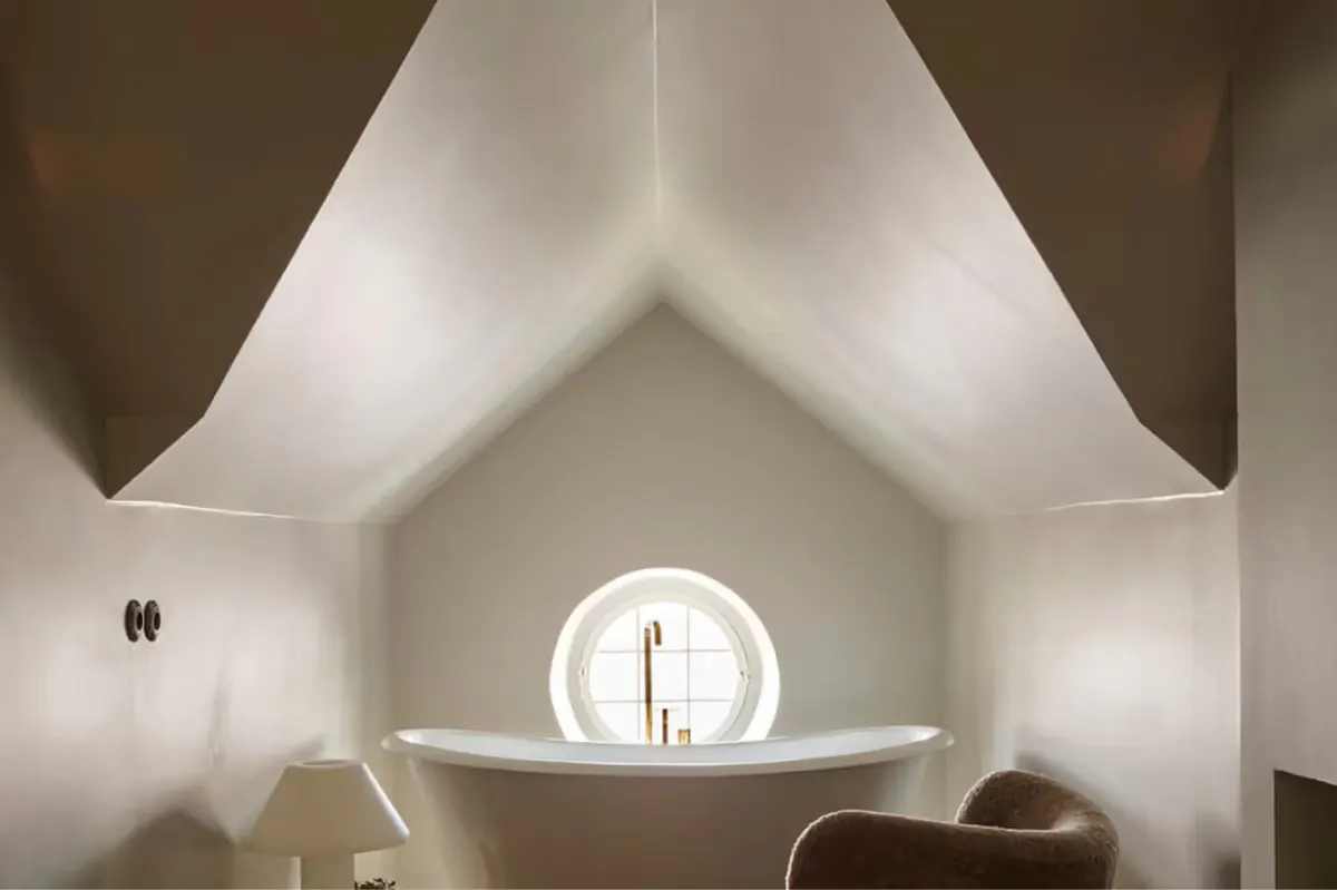 An angular white ceiling with a circular skylight opening to blue sky
