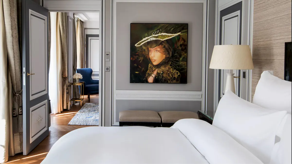 Bedroom with gray paneling, doorway to sitting room, and contemporary artwork