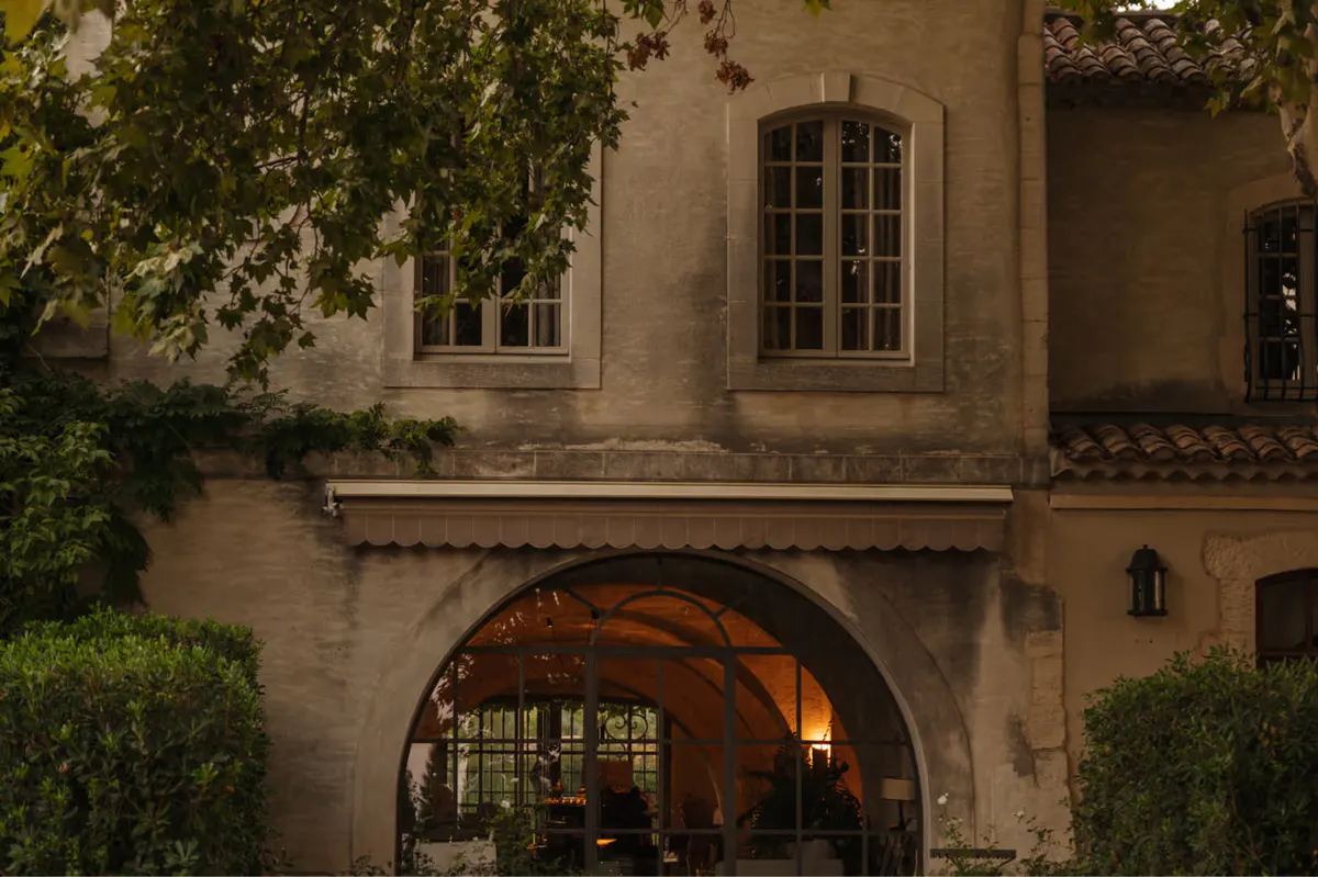 Stone facade with arched entry glowing from warm interior light at evening
