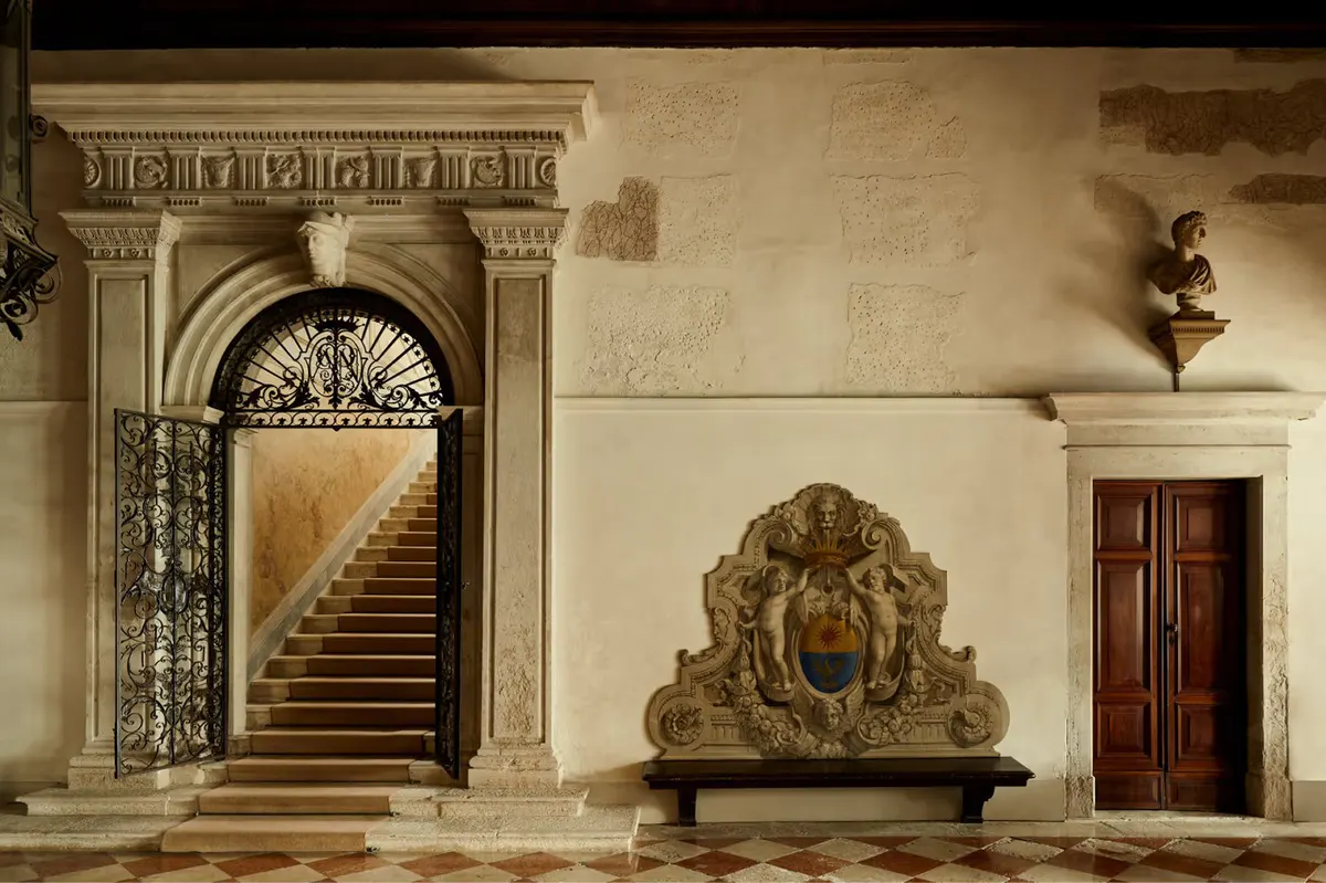The palazzo entrance hall with a monumental staircase, classical archway, and ornate stone sculpture