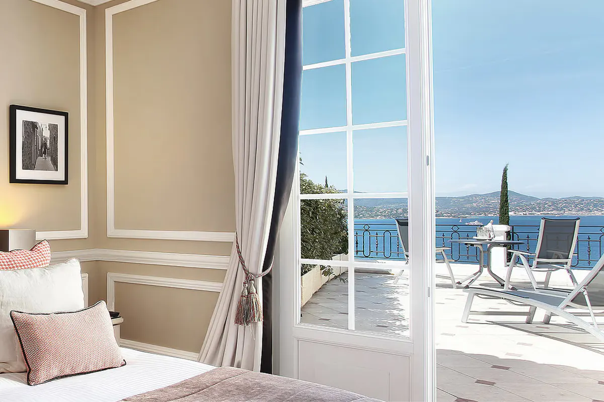 Bedroom with open glass doors to a balcony and white drapery
