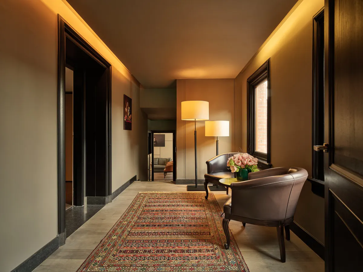 Foyer with patterned runner rug, dark doors, mirror wall, and contemporary furnishings