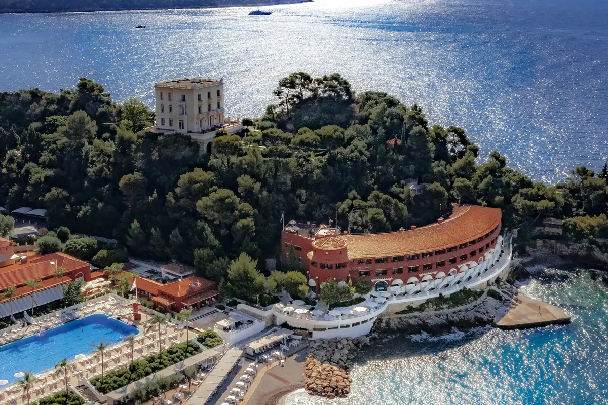 Aerial view of beachfront property with pool, gardens, and Mediterranean beyond