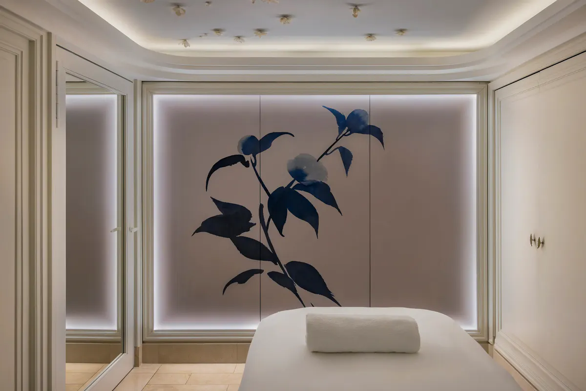 A treatment room with massage table, botanical art installation, and soft ambient light