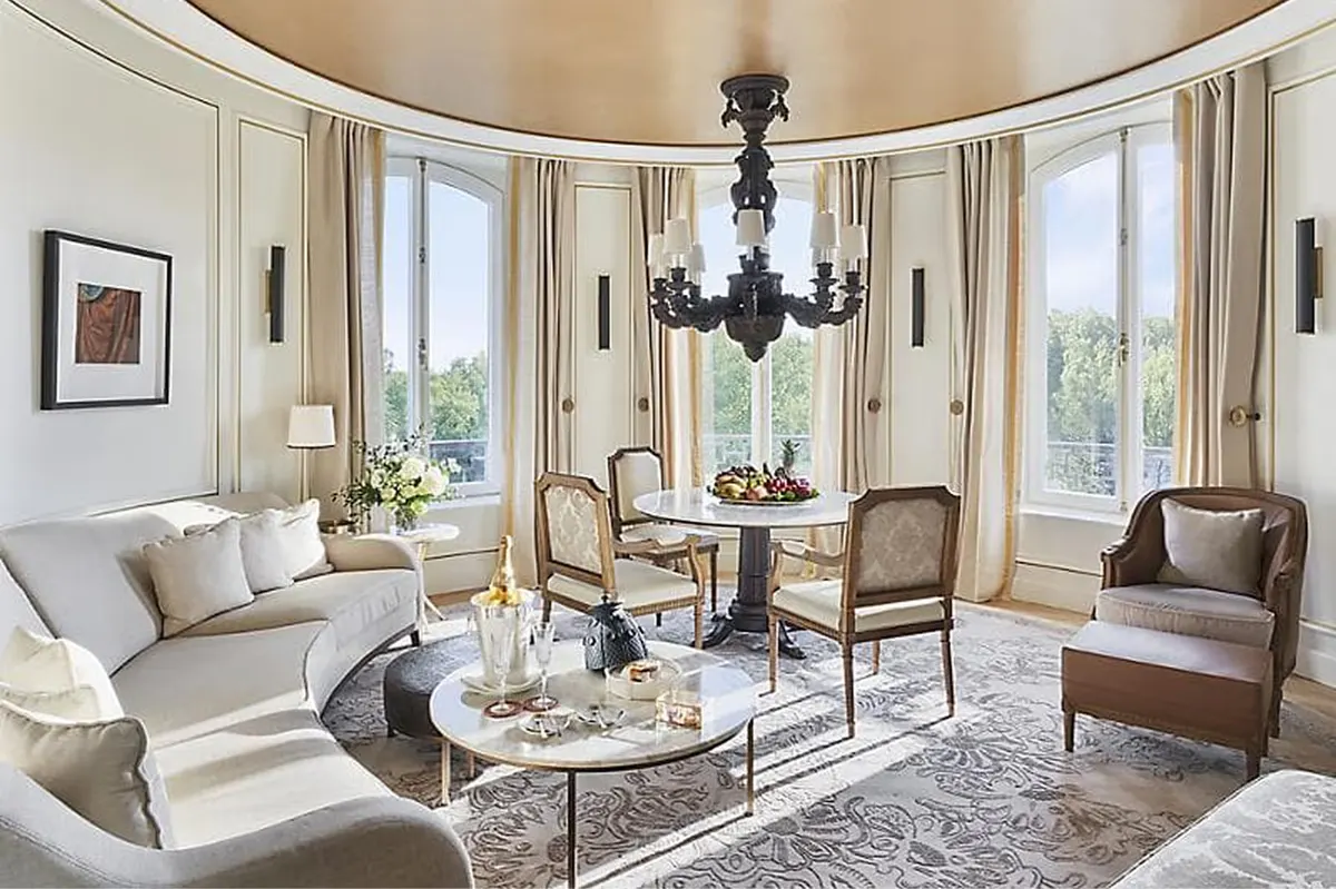 Curved parlor with black chandelier, upholstered seating, and inlaid marble floors