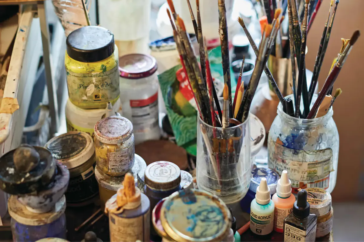 Art studio desk with brushes, jars, and painting supplies for creative work