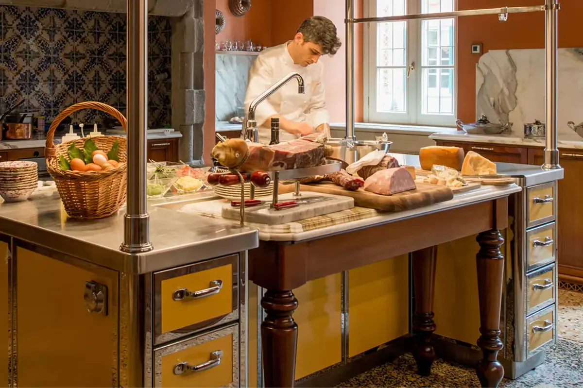 A chef at work in a cream-colored kitchen with marble countertops and copper cookware