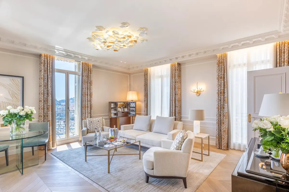 Suite living room with blue drapes, sofa seating and arched doors opening to terrace view