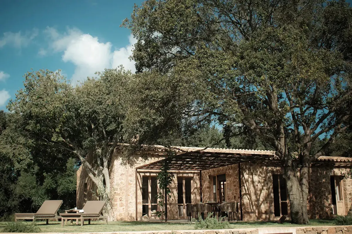Traditional stone casita building set in wooded valley landscape with bright Mediterranean light