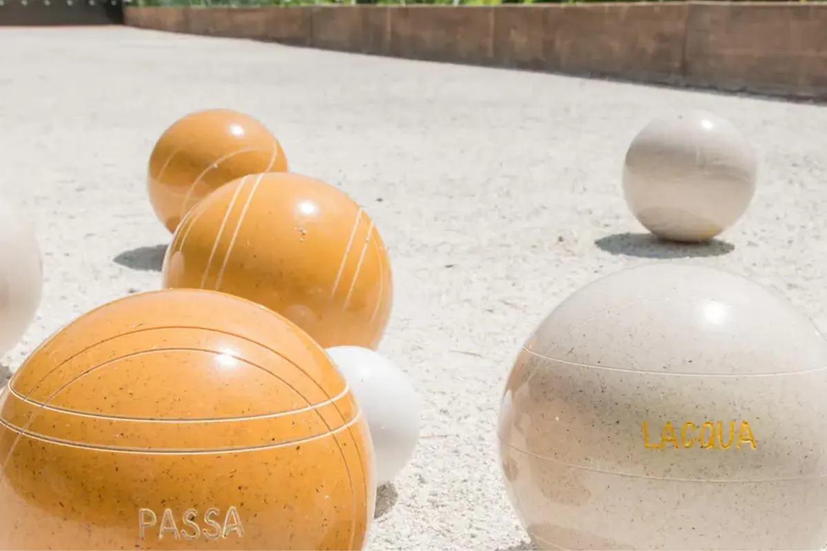 Bocce balls in tan and white on a stone surface, branded with property name