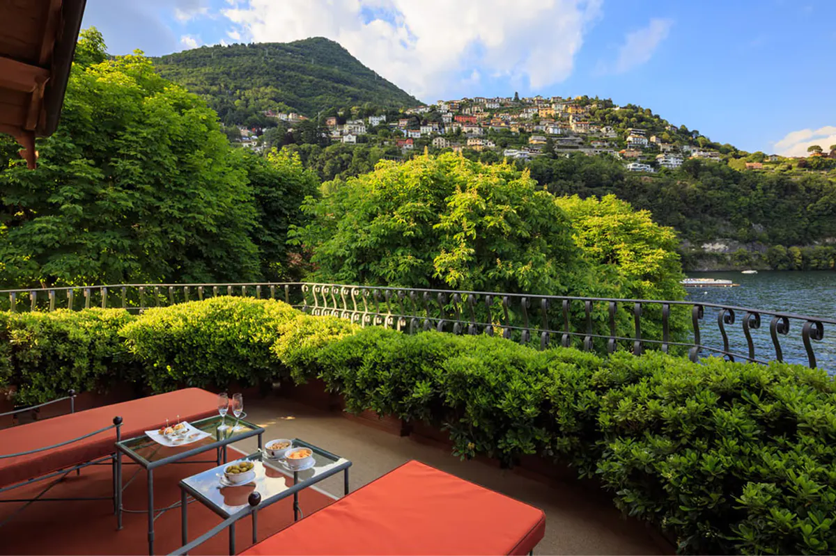Covered terrace with cream lounge seating overlooking the lake from a hillside vantage