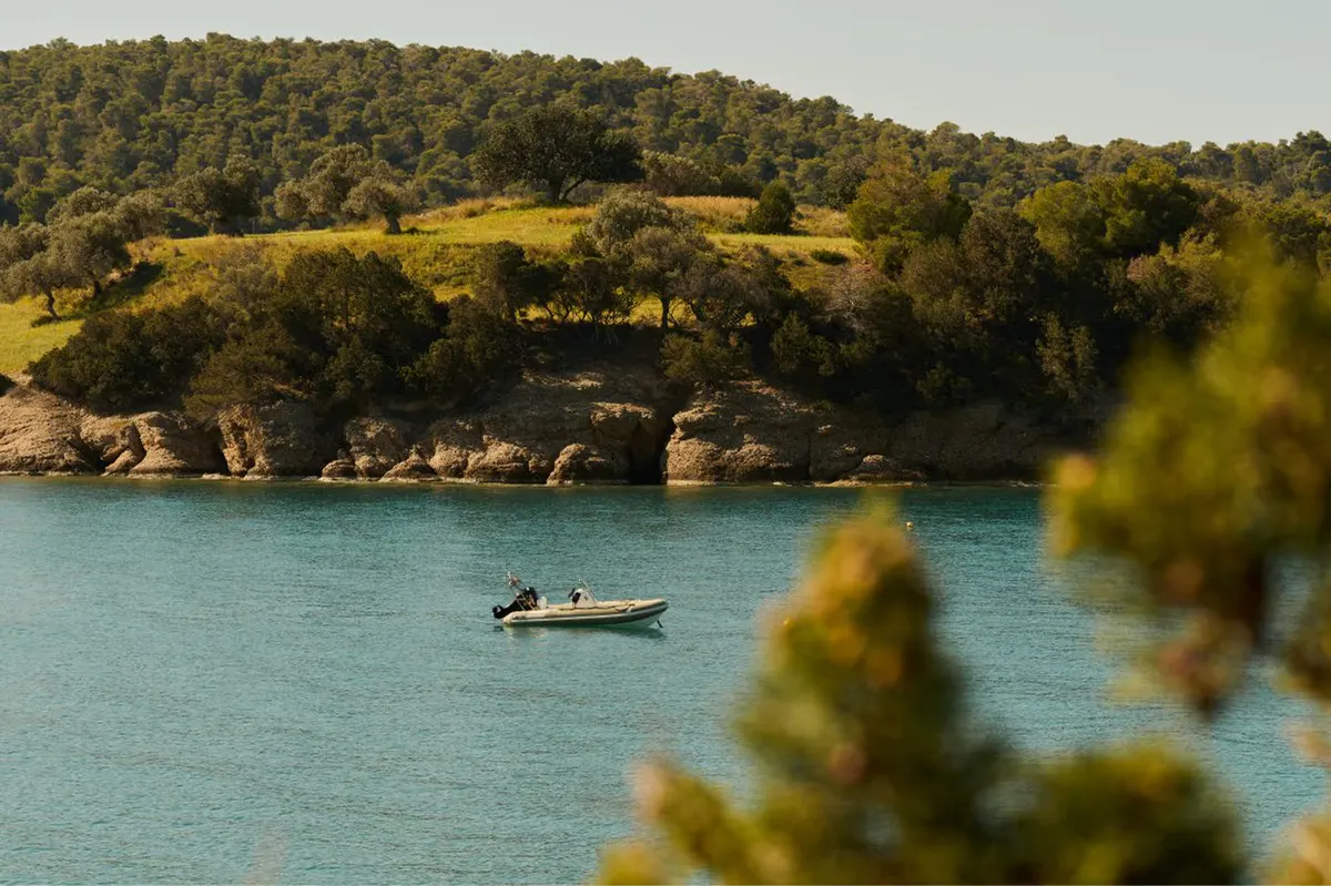 Boat moored in shallow turquoise waters near forested coast