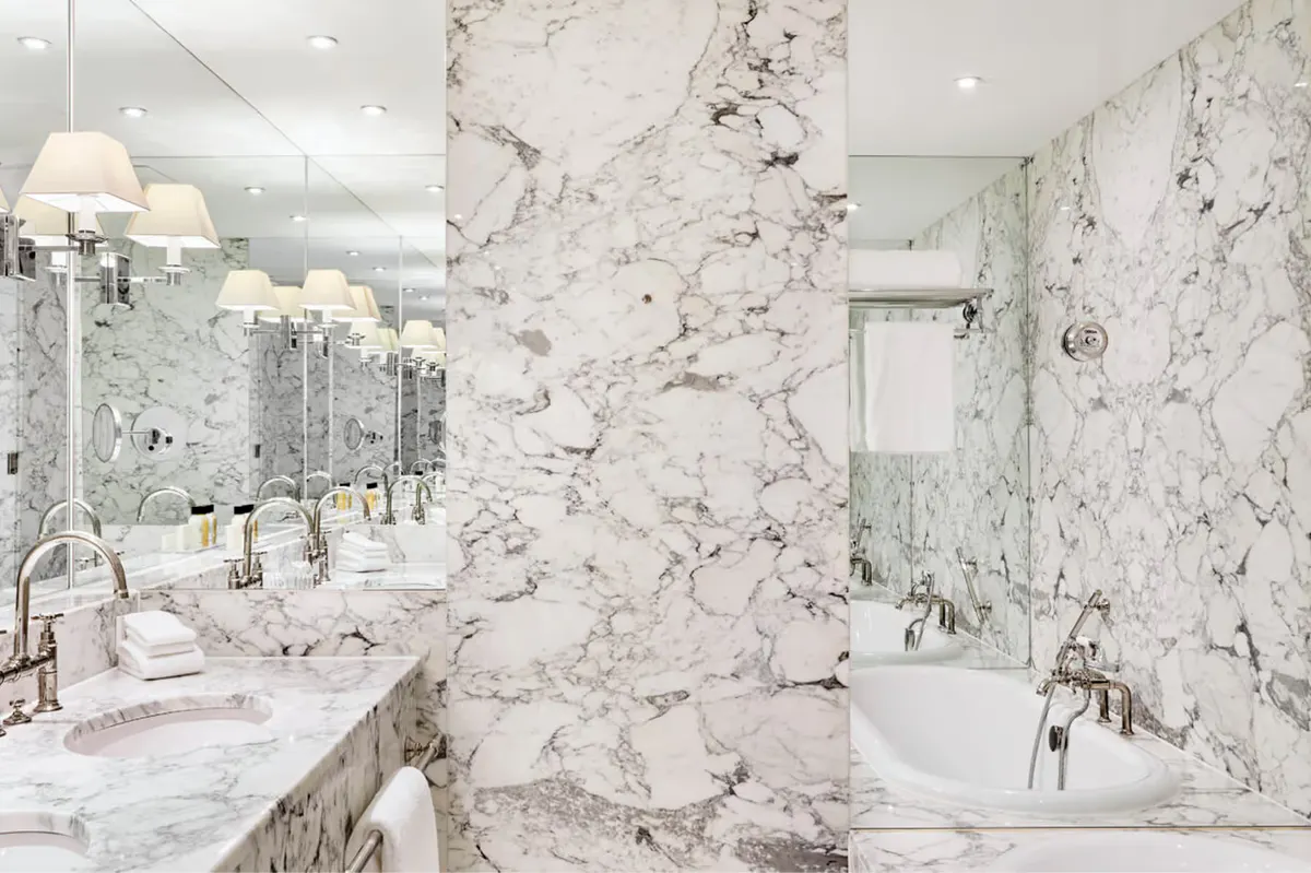 Marble bathroom with double vanity, soaking tub, and subway tile accent wall