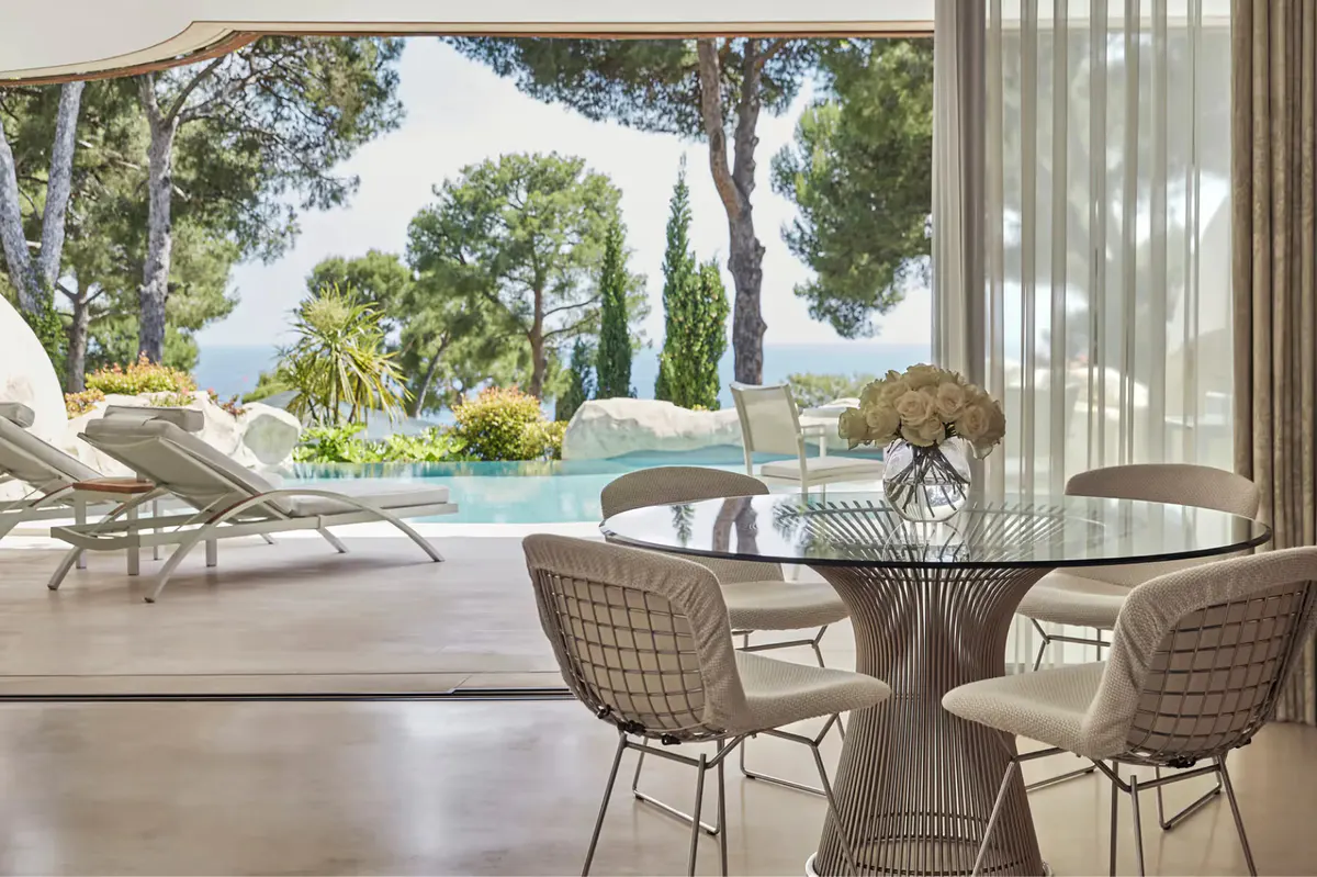 Furnished terrace with dining table and sea view through open glass doors