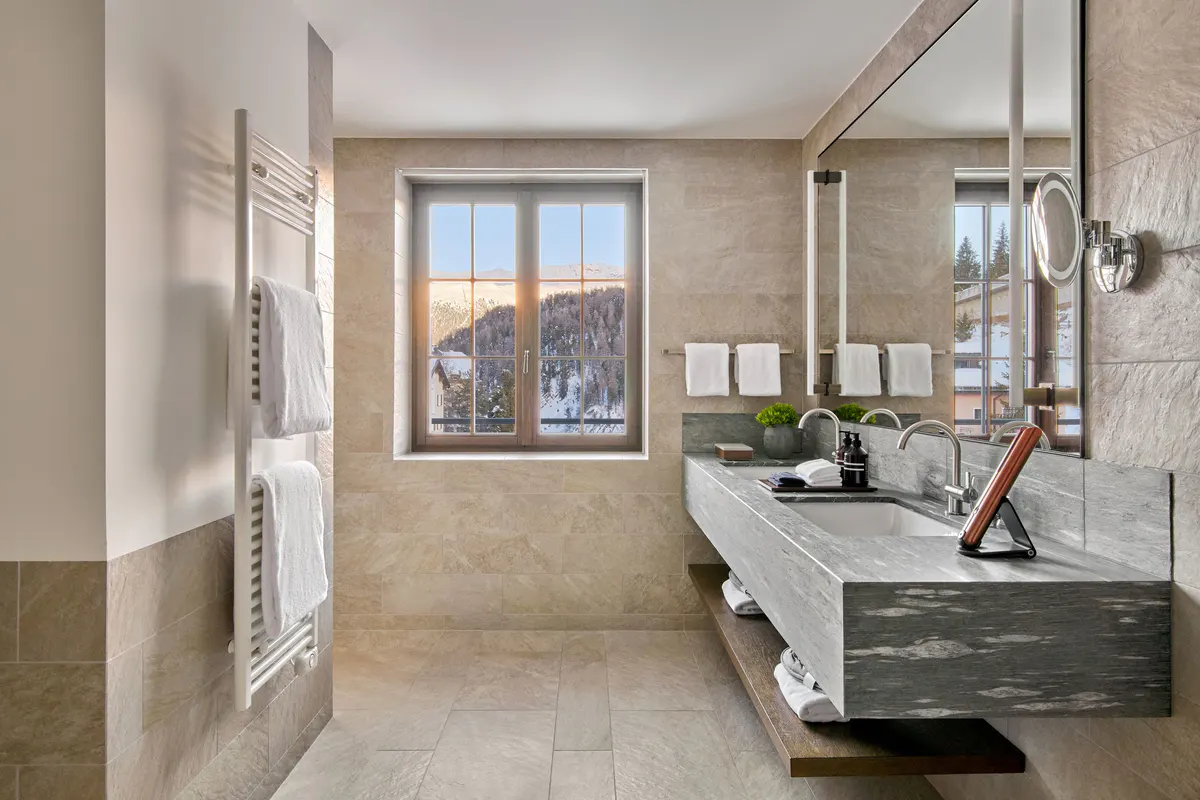 Marble bathroom with stone walls, open showers, and windows overlooking mountains