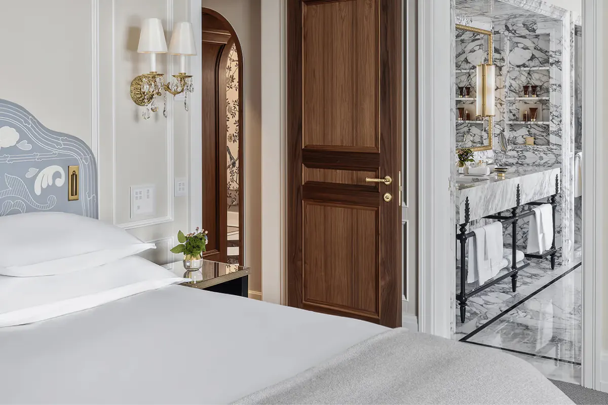 Hallway with white walls, wooden doors, and light stone flooring