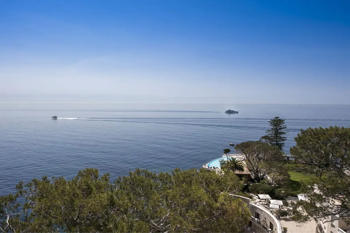 A calm Mediterranean seascape with rocky shoreline in the foreground