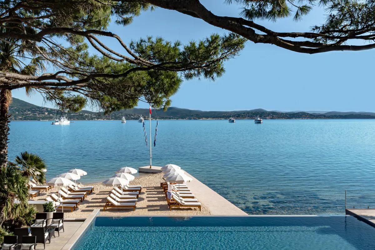 Pool and loungers with anchored boats in turquoise water