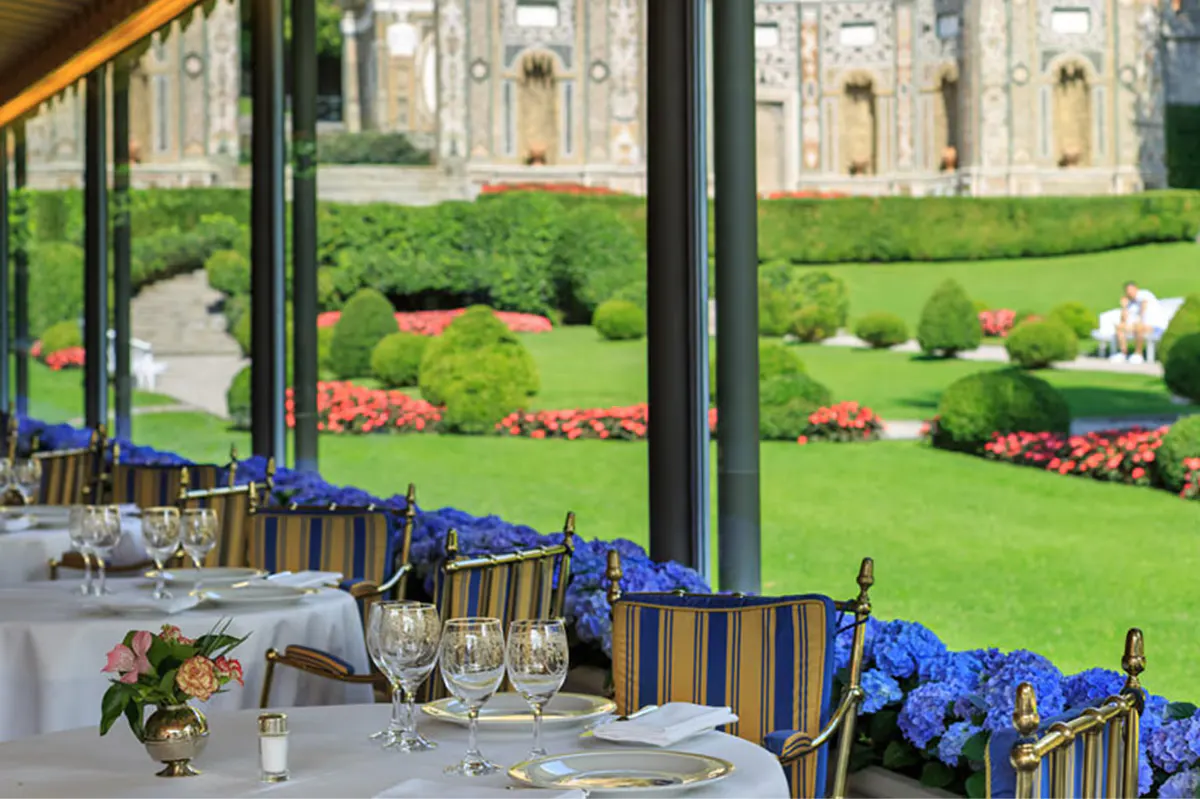 Outdoor dining pavilion with set tables overlooking the lake at dusk