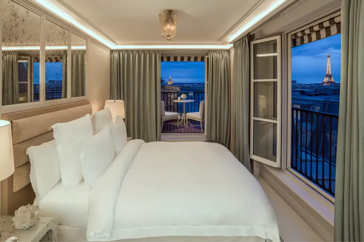 Bedroom with views of Eiffel Tower at dusk through tall French windows