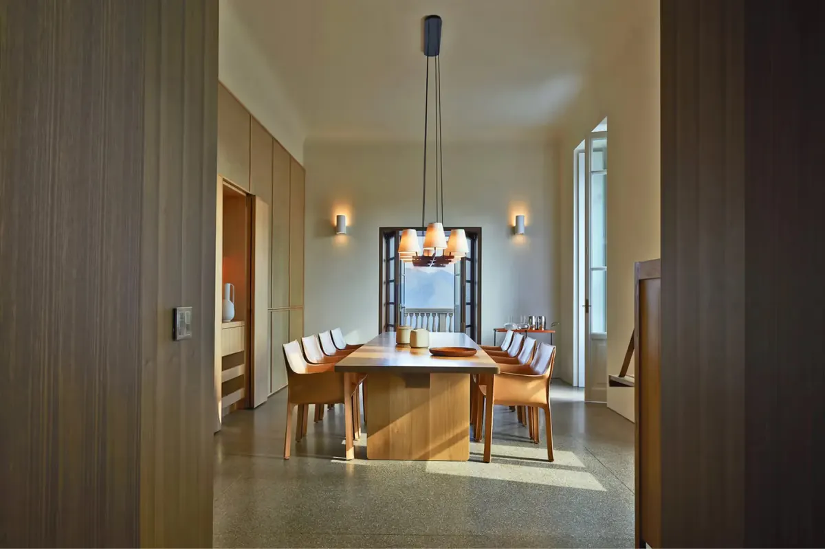A formal dining room with wooden table, tall windows, and neutral palette