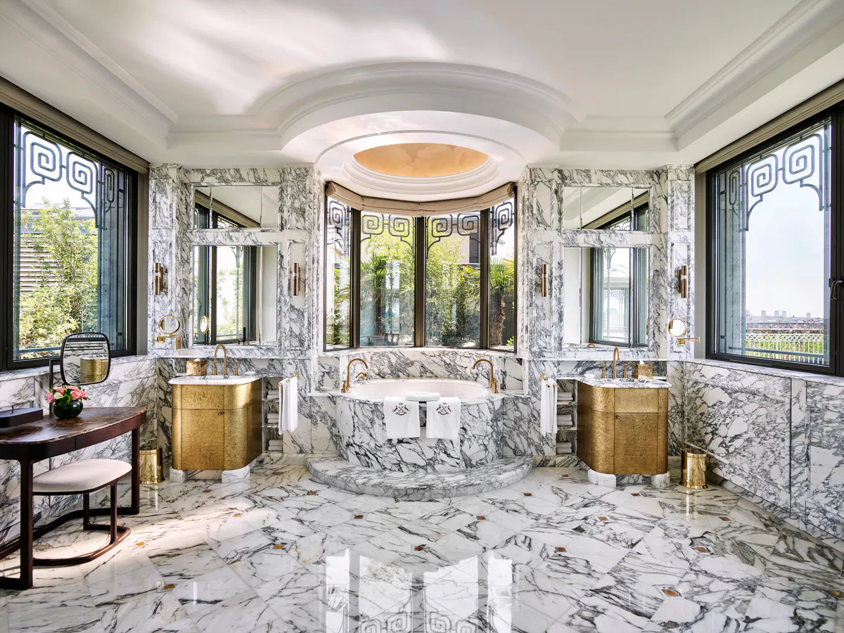 A marble bathroom with an oversized tub in cream and gilt finishes