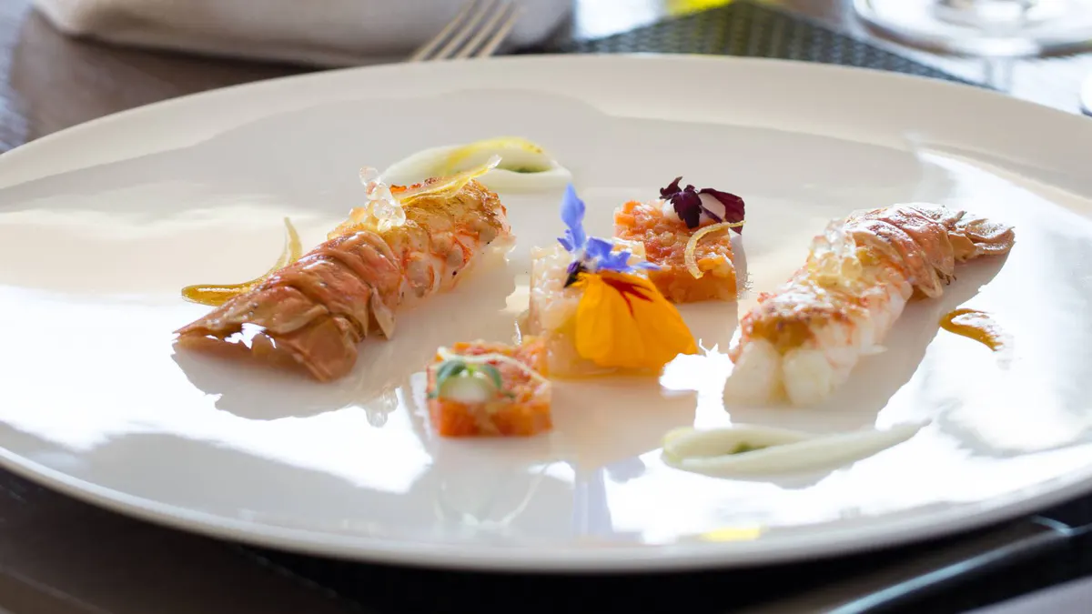 Artistic plated dish with pale protein and colorful garnishes