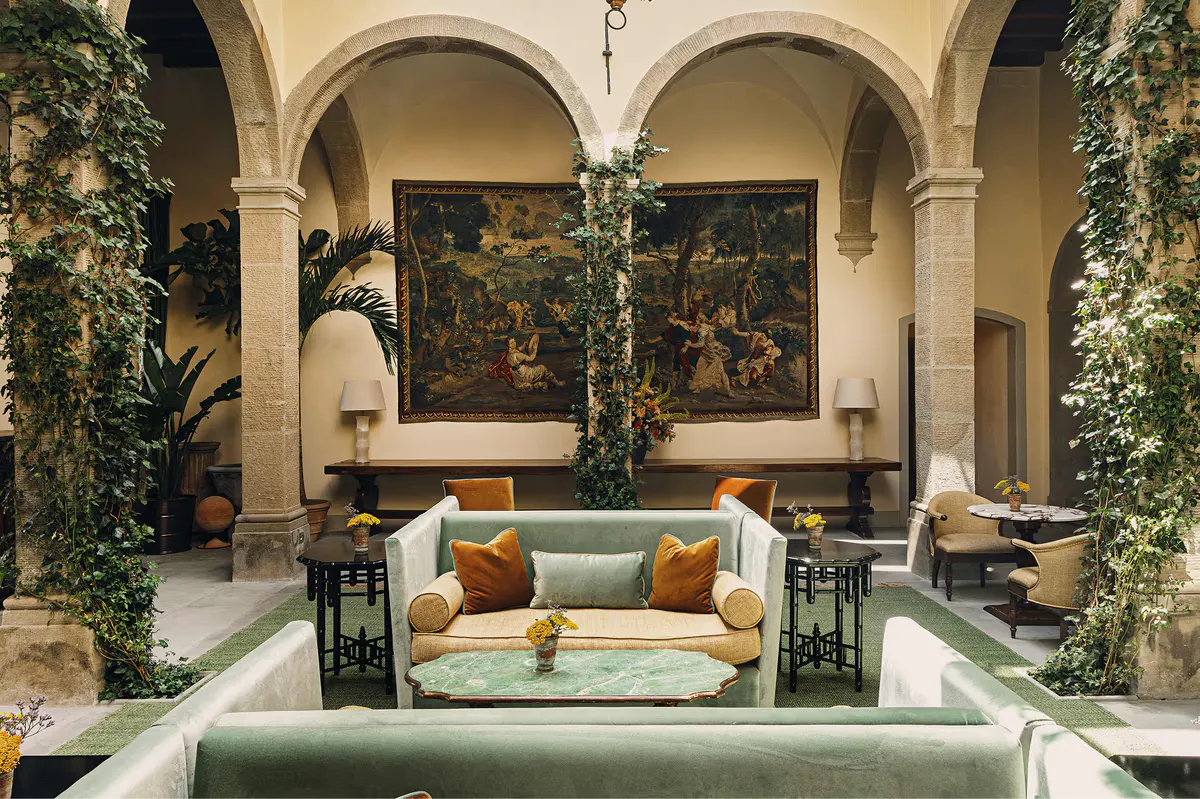 A vaulted courtyard with arched openings, green seating, and classical Italian architectural details